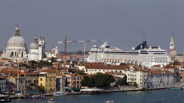 Eine große Kreuzfahrt liegt vor der Skyline von Venedig.