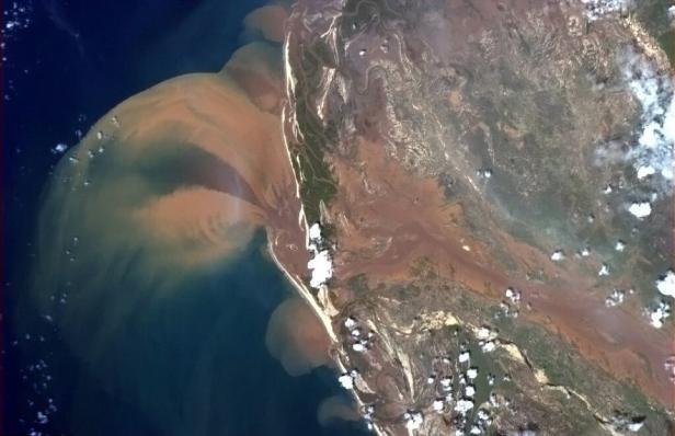 Satellitenansicht von Sedimentströmen, die ins Meer fließen.