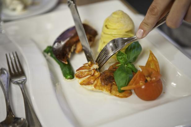 Ein Teller mit Hummer, Pasta und Gemüse wird mit Messer und Gabel angerichtet.