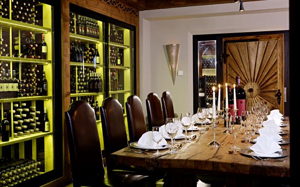 Ein festlich gedeckter Tisch in einem Weinkeller mit vollen Regalen im Hintergrund.