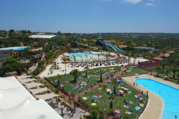 Ein Überblick über einen Wasserpark mit Pools, Rutschen und vielen Menschen.