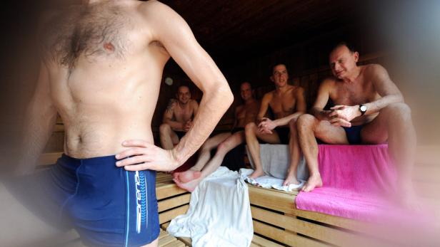 Mehrere Männer sitzen in einer Sauna.