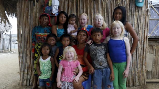 Eine Gruppe von indigenen Kuna-Kindern und Erwachsenen posiert vor einem Haus mit Wänden aus Bambusrohren.