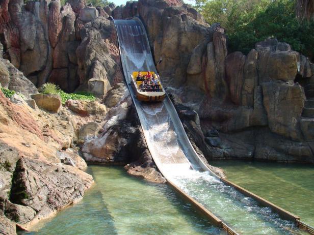 Eine Gruppe von Menschen fährt mit einem Boot eine steile Wasserrutsche hinunter.