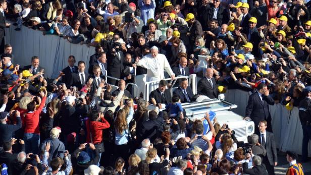 Papst Franziskus winkt der Menge aus einem offenen Wagen.
