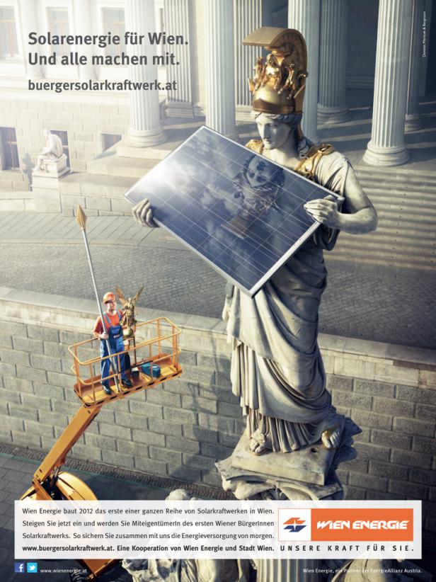 Eine Statue in Wien hält ein Solarmodul, während ein Arbeiter daneben steht.