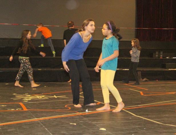 Eine Frau gibt einem jungen Mädchen Anweisungen auf einer Bühne.