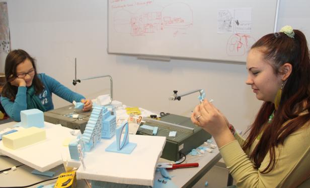 Zwei junge Frauen arbeiten an Modellen aus Styropor in einem hellen Raum.