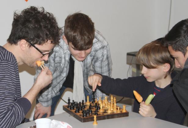 Eine Gruppe von Personen spielt Schach und isst Eis am Stiel.