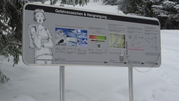Eine Informationstafel über Gefahrenzeichen und Hangneigung im Schnee.