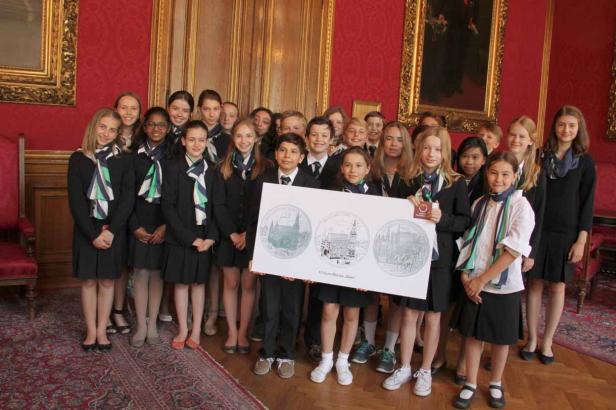 Eine Gruppe von Schülern hält eine Tafel mit Abbildungen von Wiener Münzen.