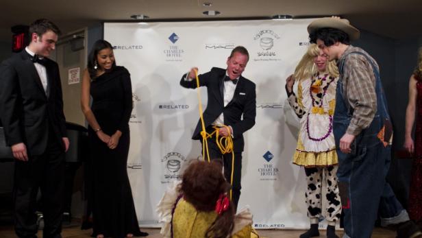 Kiefer Sutherland mit einem Seil auf einer Veranstaltung, umgeben von kostümierten Personen.