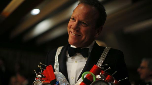 Kiefer Sutherland im Smoking mit einer Spielzeug-Bombe in der Hand.