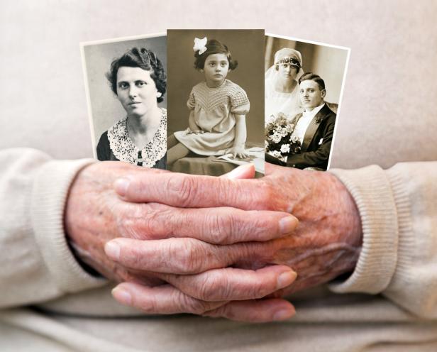 Alte Hände halten drei Schwarz-Weiß-Fotografien von Familienmitgliedern.