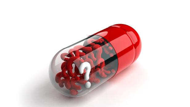 Eine rote Kapsel gefüllt mit roten Fragezeichen und einem weißen Fragezeichen.