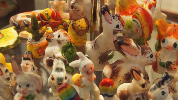 Eine Sammlung von bemalten Tierfiguren, darunter viele Hasen, ein Kaktus und ein Hahn.