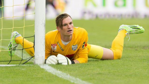 Ein Torwart liegt im gelben Trikot auf dem Rasen neben dem Tor.