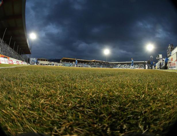 Ein Fußballstadion unter einem dunklen, bewölkten Himmel.