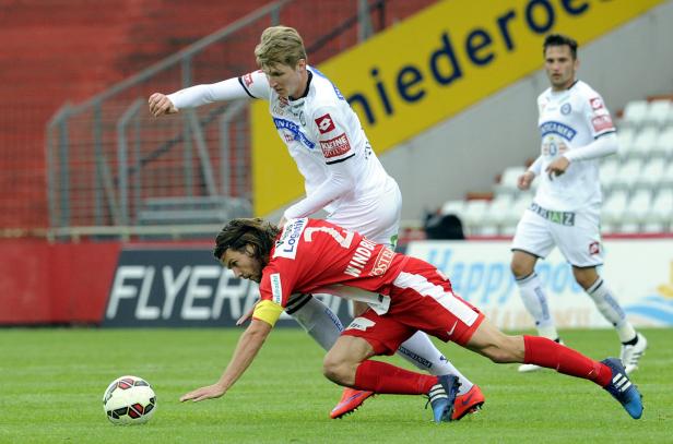 Zwei Fußballspieler kämpfen um den Ball auf dem Spielfeld.