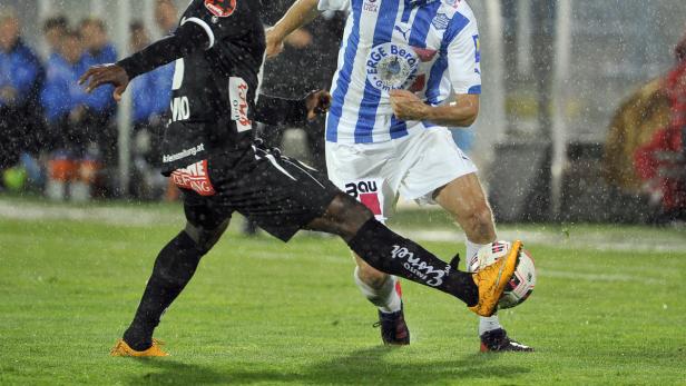 Zwei Fußballspieler kämpfen im Regen um den Ball.