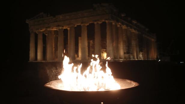 Eine Feuerschale brennt vor dem Parthenon in Athen bei Nacht.