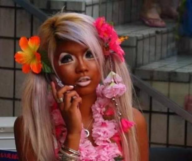 Eine Frau im Ganguro-Stil telefoniert mit Blumen im Haar und einer Blumenkette um den Hals.
