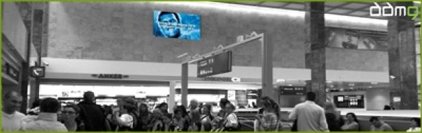 DDMG - MediaWall Menschenmenge in einem Flughafen-Terminal unter einer Werbetafel.