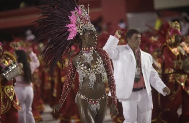Eine Frau mit Federkopfschmuck und Schmuckkleidung tanzt beim Karnevalsumzug.