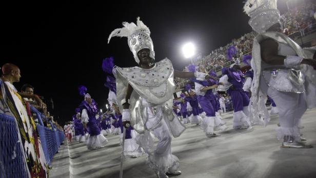Eine Gruppe von Menschen in aufwendigen Kostümen nimmt an einer Parade teil.