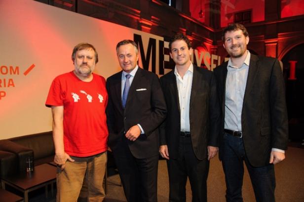 Eine Gruppe von vier Männern posiert für ein Foto vor einer Wand mit dem Schriftzug „Media“.