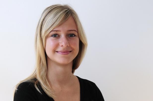 Porträt einer lächelnden jungen Frau mit blonden Haaren.