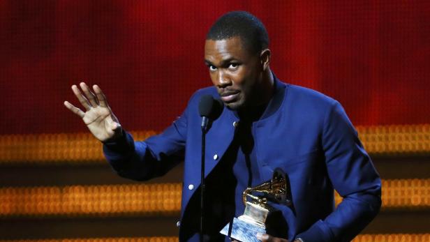 Frank Ocean hält eine Grammy-Trophäe in der Hand und winkt.