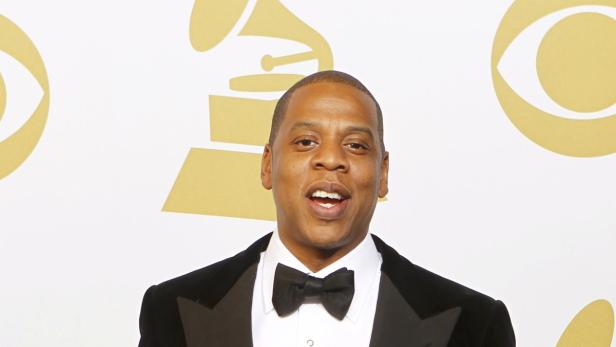 Jay-Z in einem Smoking vor dem Hintergrund des Grammy-Logos.
