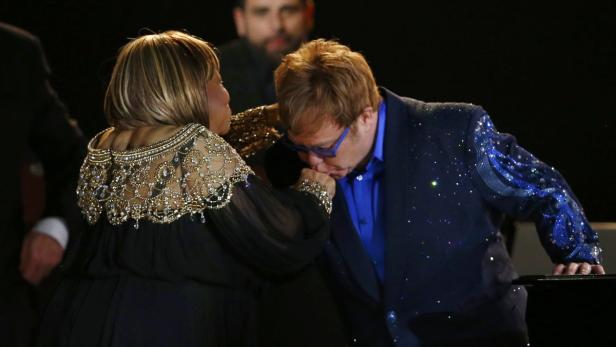 Elton John küsst Mary J. Bliges Hand.