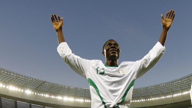 Ein nigerianischer Fußballspieler jubelt mit erhobenen Armen in einem Stadion.