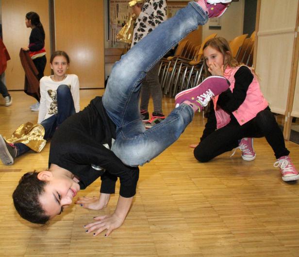 Ein Mädchen macht einen Handstand, während andere Mädchen im Hintergrund sitzen und zusehen.