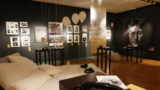 Ein Ausstellungsraum mit Fotos von John Lennon und einem großen Porträt von ihm.