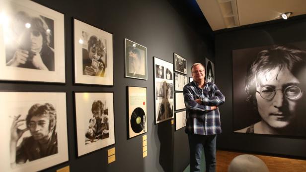Ein Mann steht in einer Ausstellung mit Porträts von John Lennon.