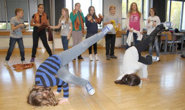 Zwei Mädchen machen Kopfstand vor einer Gruppe von Zuschauern.