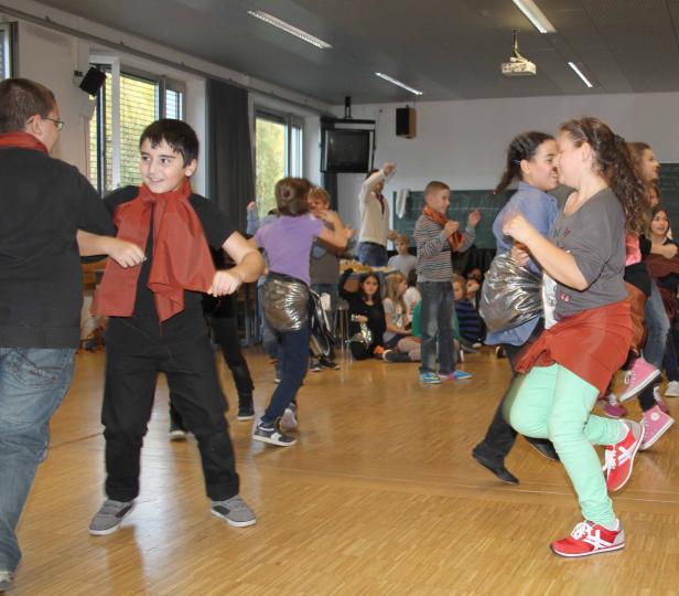 Eine Gruppe von Kindern tanzt in einem Raum mit Holzfußboden.