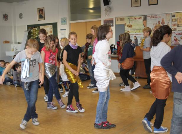 Eine Gruppe von Kindern probt in einem Klassenzimmer für eine Aufführung.