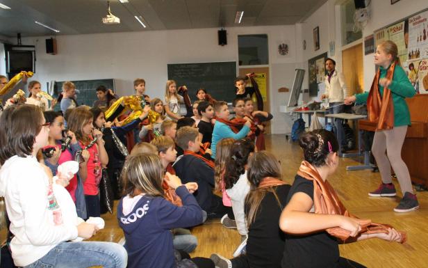 Eine Gruppe von Kindern nimmt an einer Theateraufführung in einem Klassenzimmer teil.