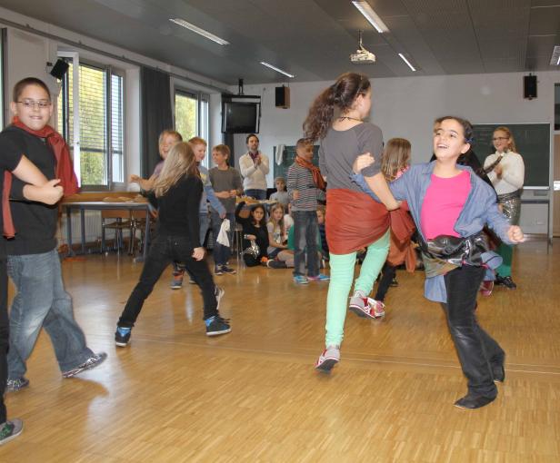 Eine Gruppe von Kindern tanzt in einem hellen Raum.