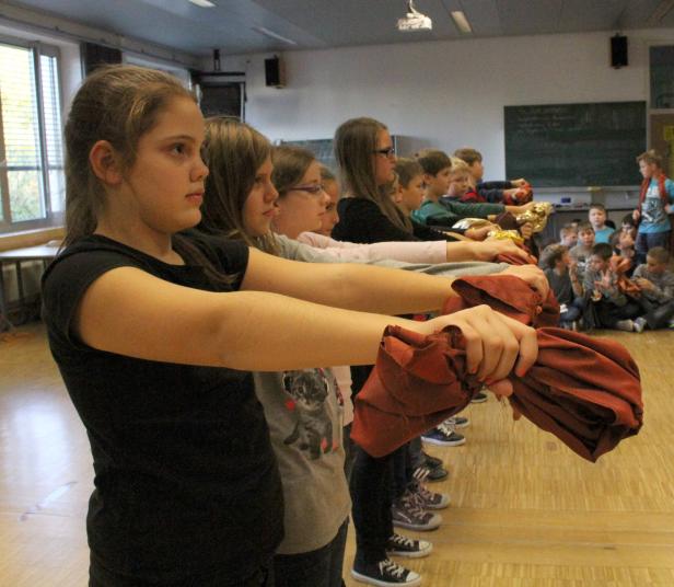 Eine Gruppe von Schulkindern führt eine Performance mit Tüchern auf.