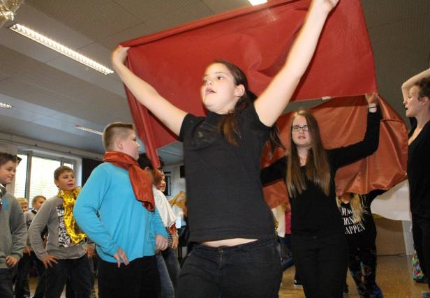 Eine Gruppe von Jugendlichen hält ein großes, rotes Tuch hoch.