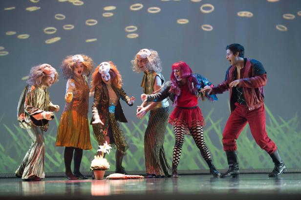 Eine Gruppe von Schauspielern in Kostümen und Masken steht auf einer Bühne.