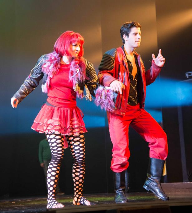 Zwei Darsteller in extravaganten Kostümen stehen auf einer Bühne.