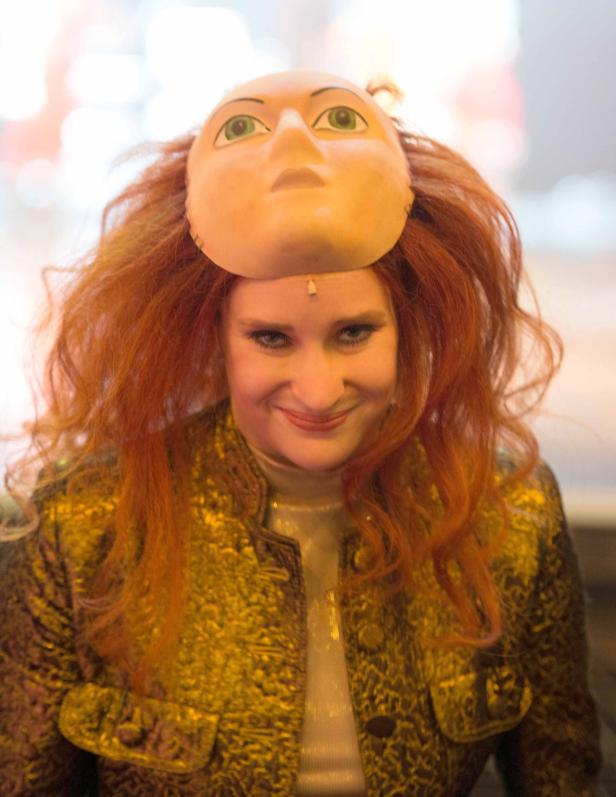 Eine Frau mit roten Haaren trägt eine Maske auf dem Kopf.