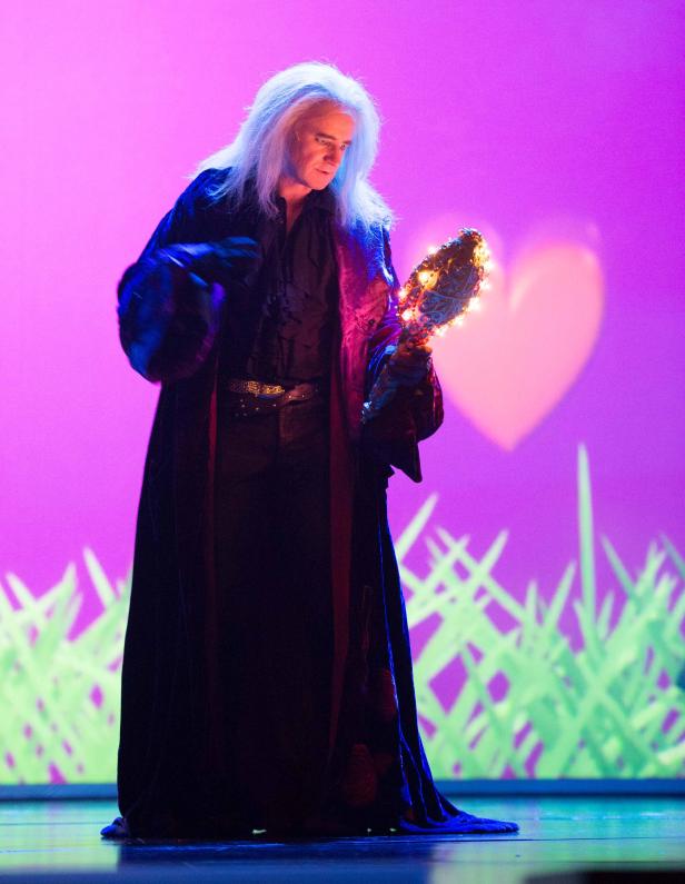 Eine Person in einem dunklen Gewand hält einen verzierten Spiegel in der Hand.