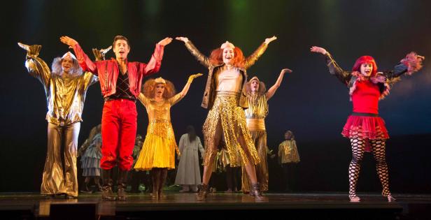 Eine Gruppe von Darstellern in farbenfrohen Kostümen auf einer Bühne.